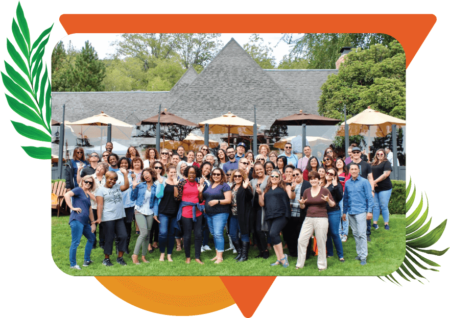 A large group of diverse inviduals posing together and smiling in front of a building outdoors