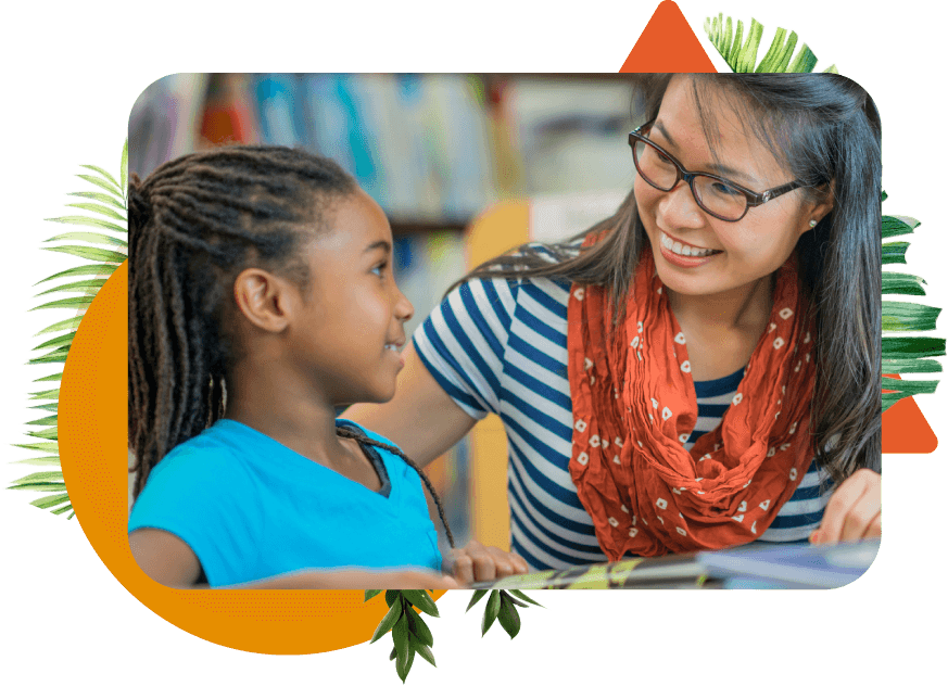 A young Asian elementary school female teacher in glasses smiling with a young black female student