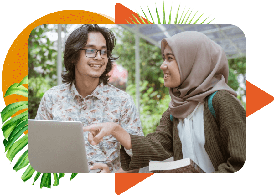 Two college-age peers, a male with glasses and long hair and a female with a hair scarf, smiling and pointing at a laptop outdoors