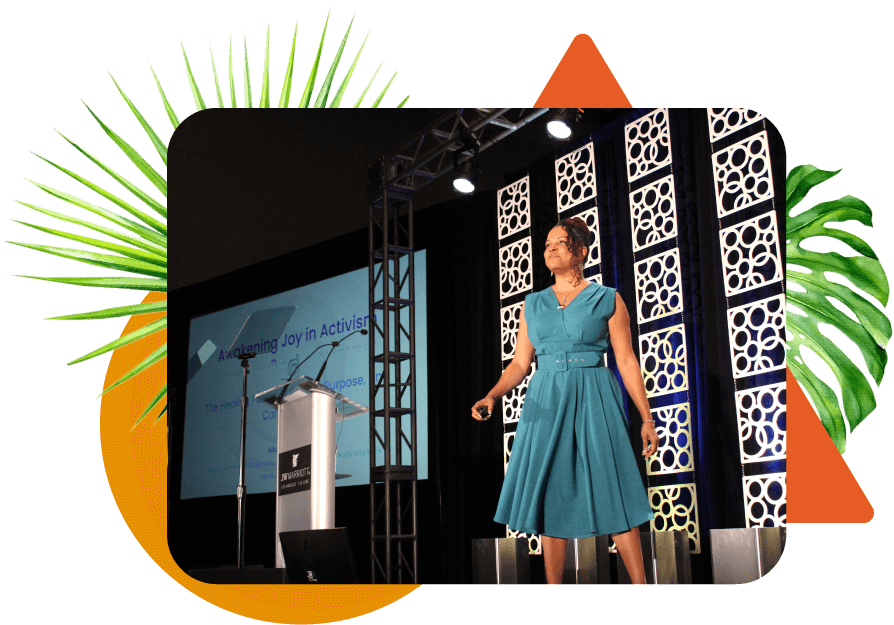 Dr. Niki speaking on a large stage in a teal blue dress