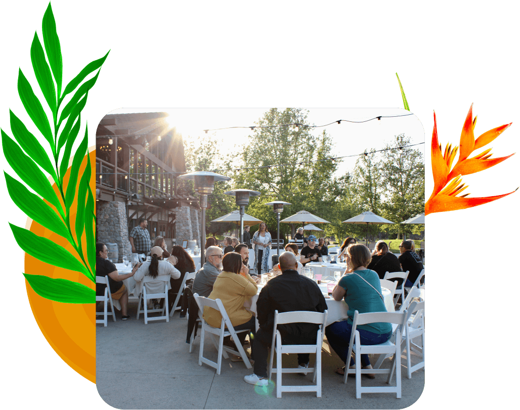 Several large round tables with diverse individuals seated together outdoors on a patio